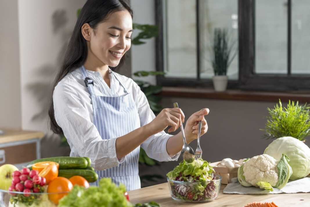 mar18-happy-woman-preparing-healthy-salad-kitchen